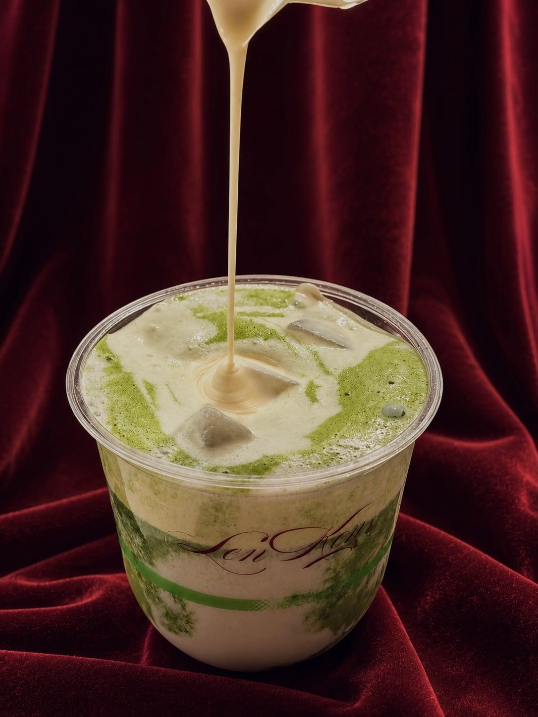 Cream poured in a ribbon over an iced Lenken matcha, against burgundy velvet.